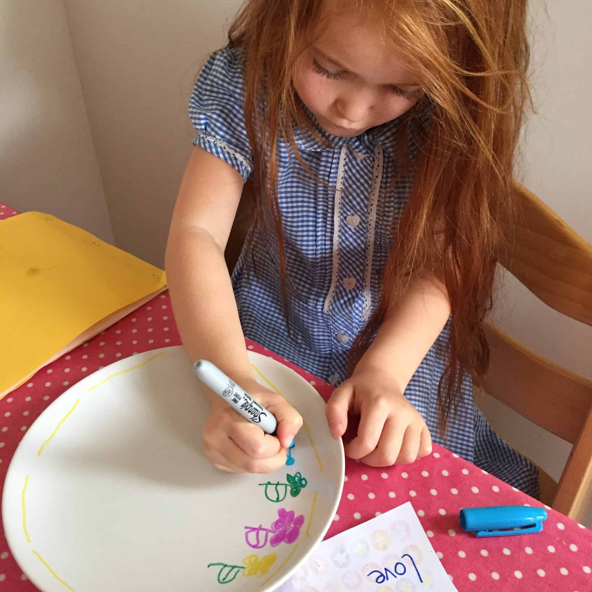 Ava decorating a plate with Sharpie pens for Father's Day