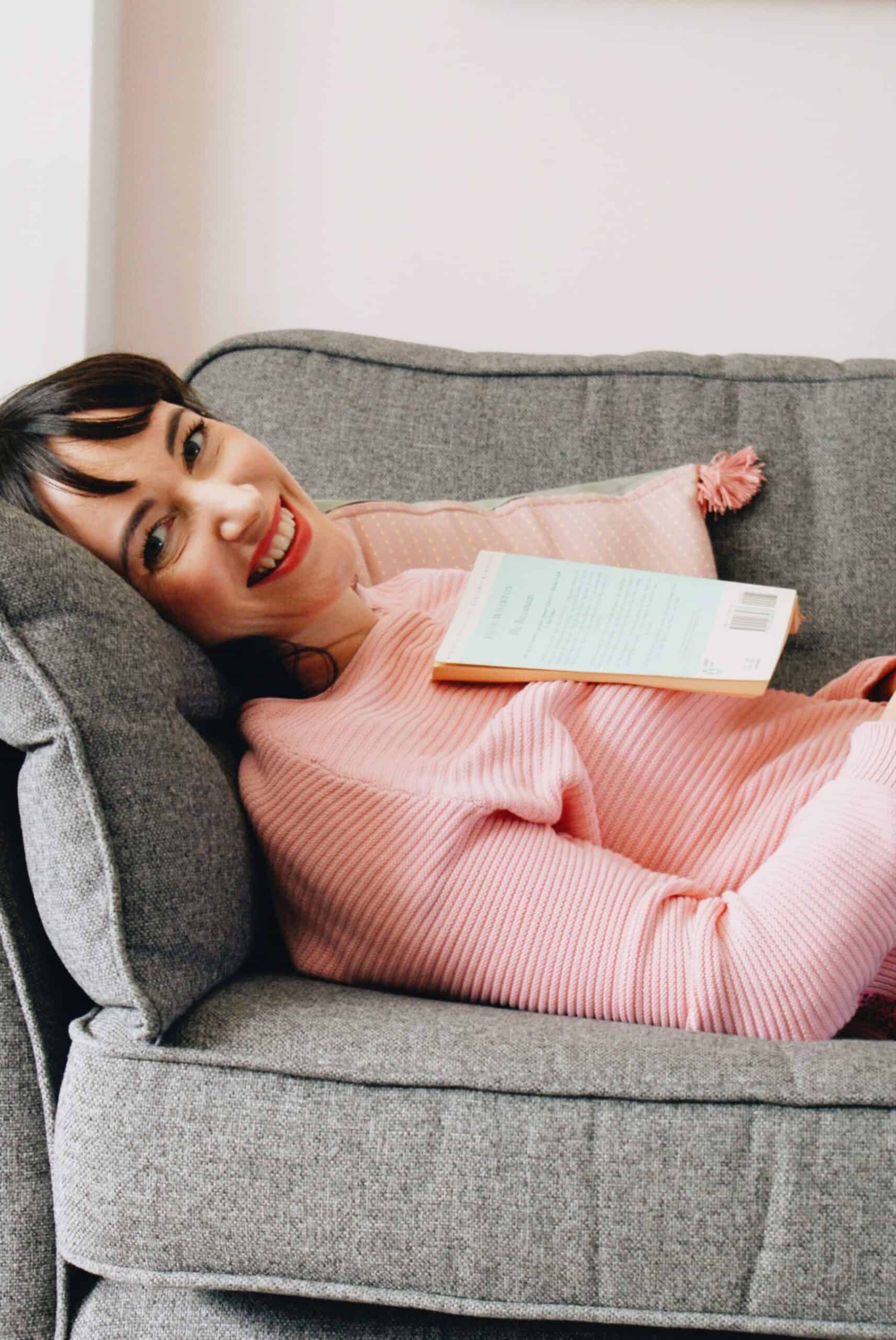Eco-Blogger Becky lying on a sofa in a pink jumper