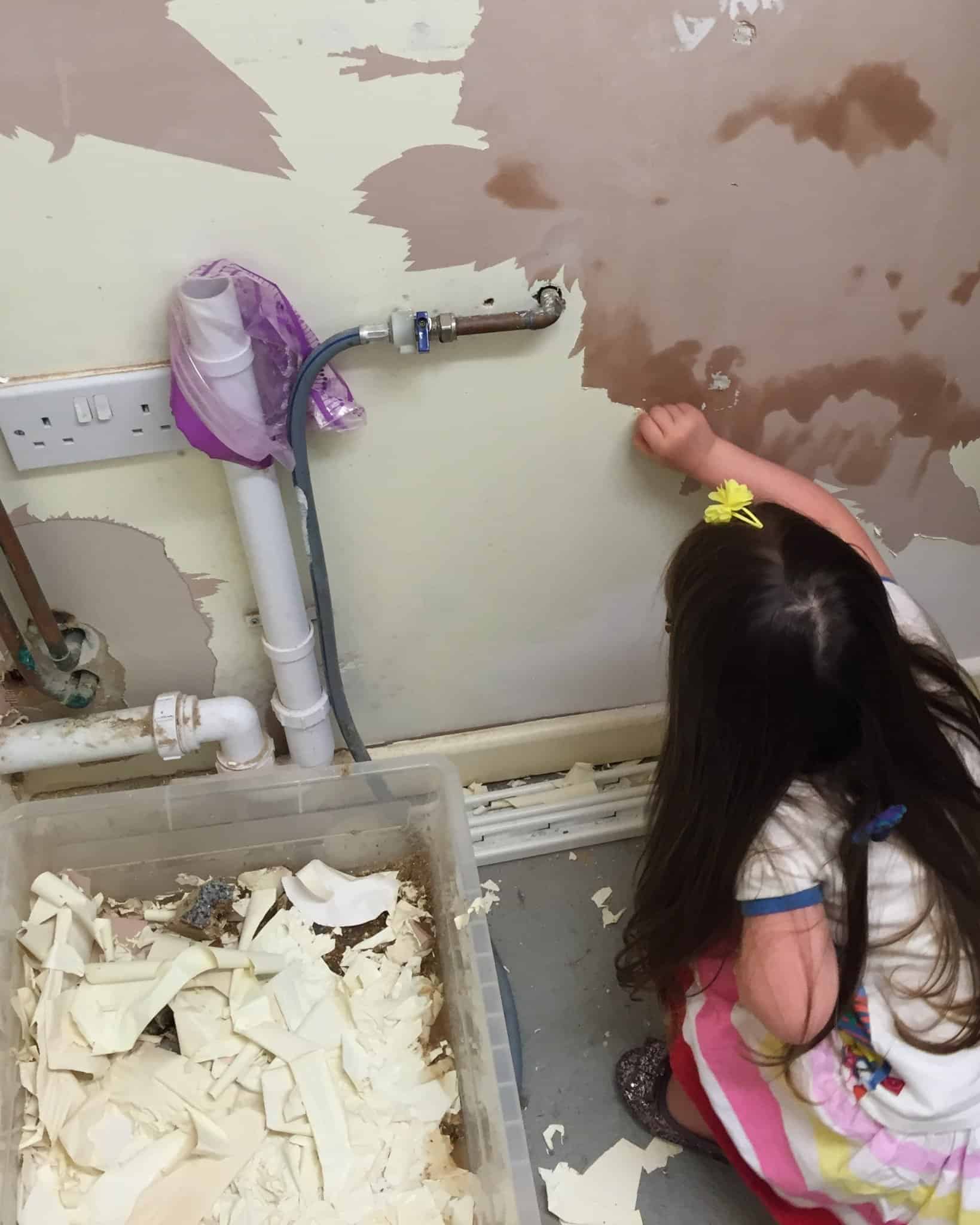 Thea peeling old paint off the utility room wall