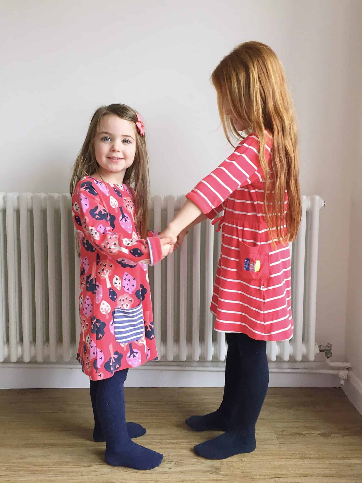 Two girls wearing Red Piccalilly ethical kids clothes holding hands