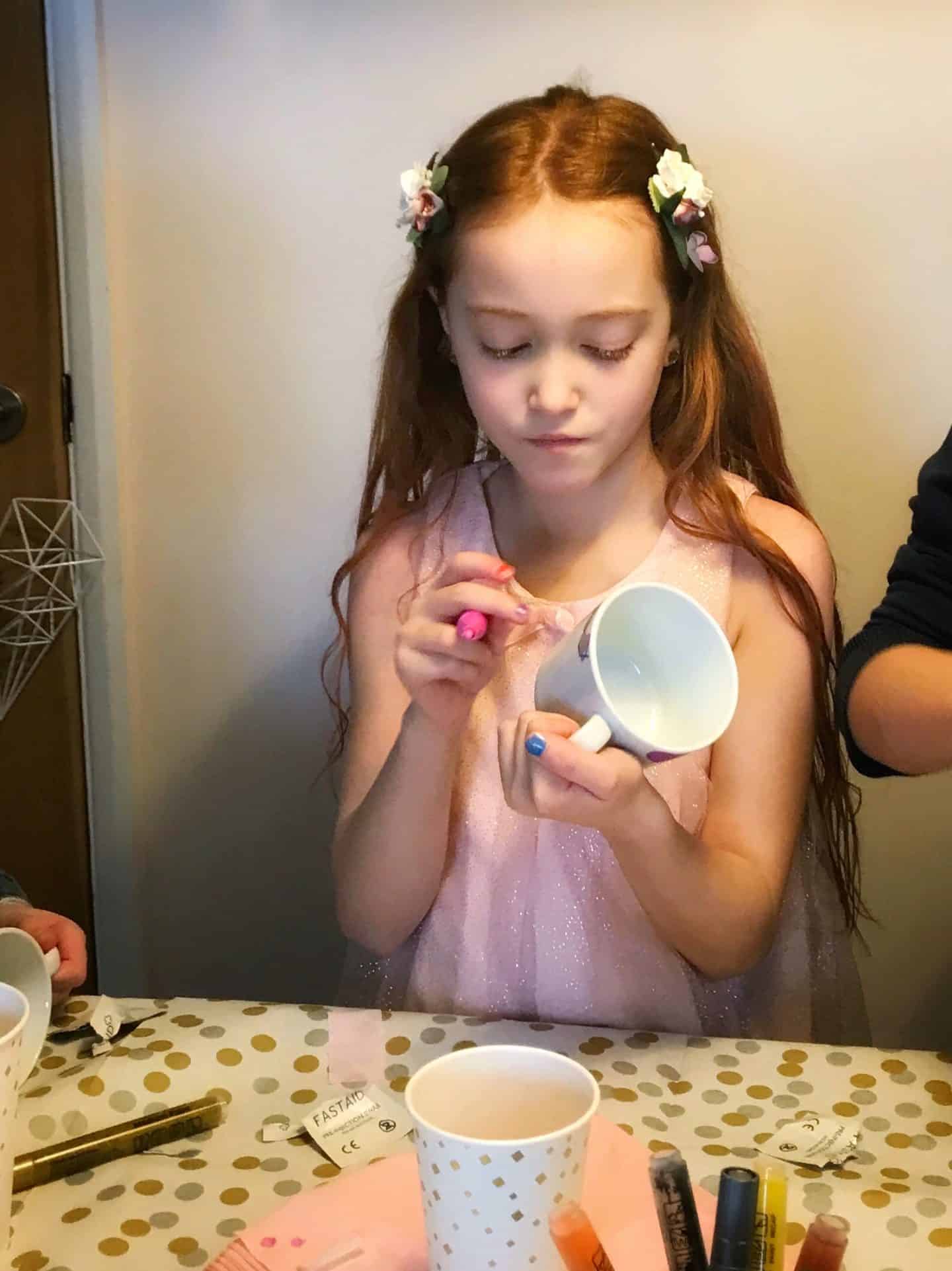 The birthday girl decorating a mug with ceramic markers