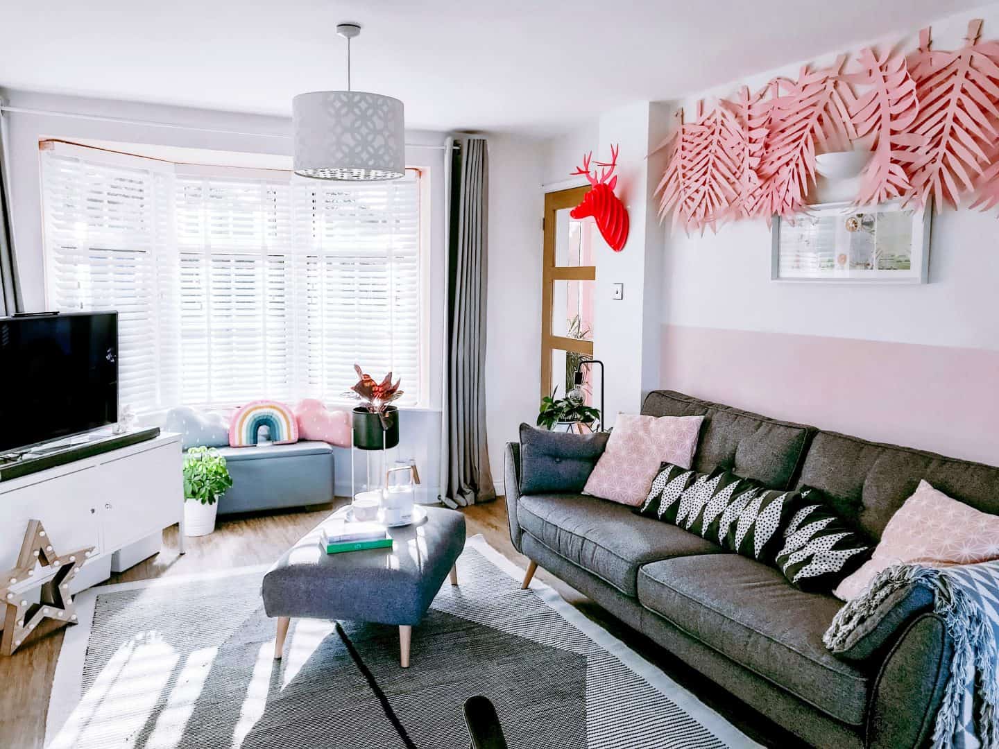 Monochrome lounge with pink acccents and white wooden blinds with tapes
