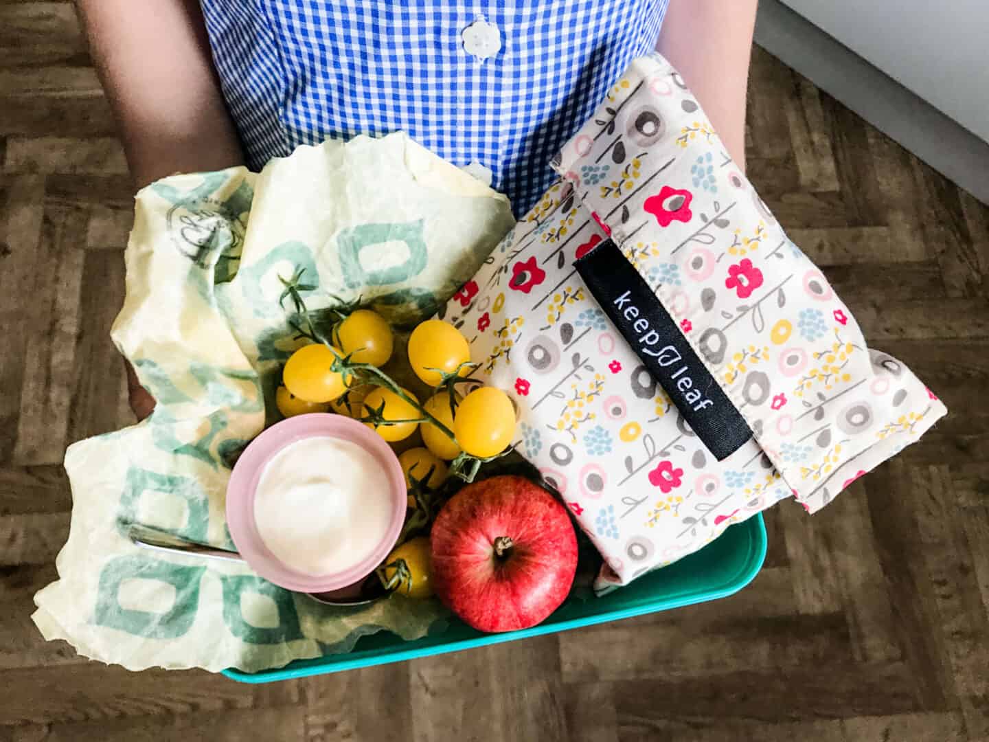 A less-plastic lunch box with a reusable sandwich bag, tomatoes in a beeswax wrap and home made yoghurt in a reusable pot