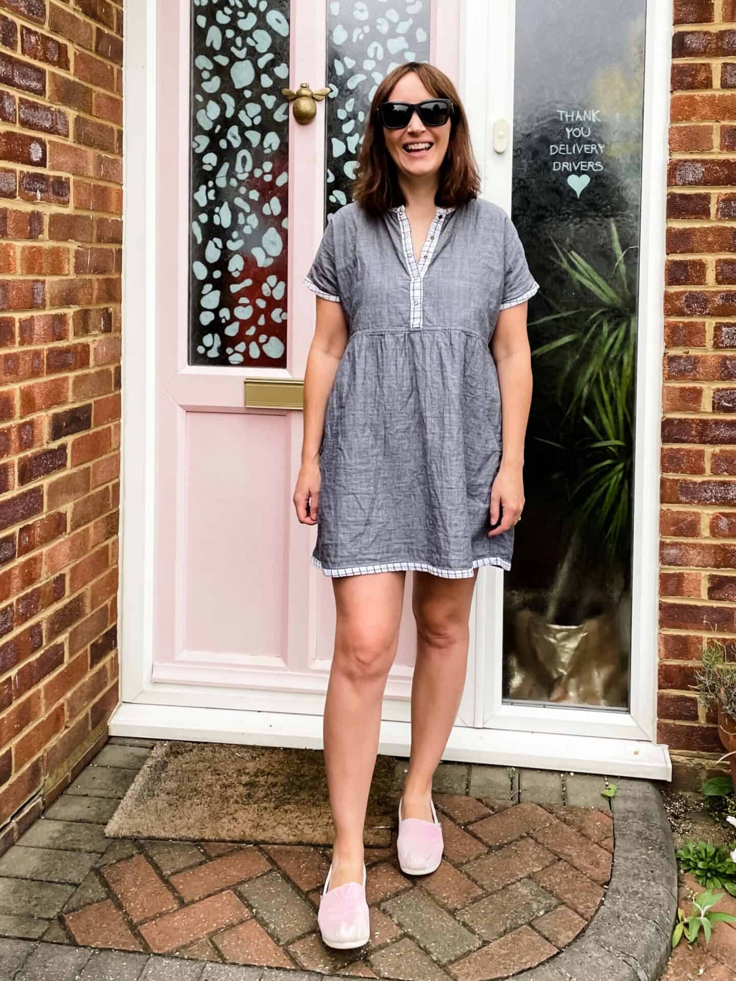 Becky Pink wearing a GOTS organic Turtledove London dress in front of her pink front door