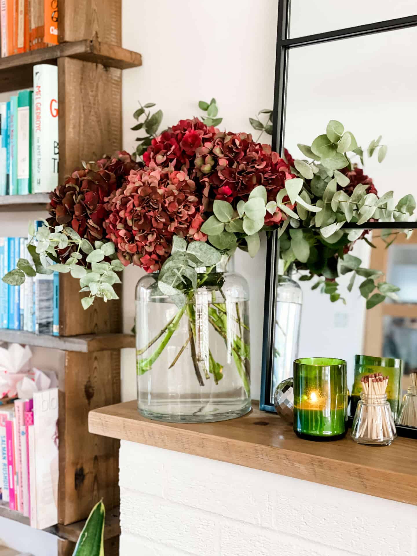Hydranga bouquet on a wooden shelf in front of a mirror and book case