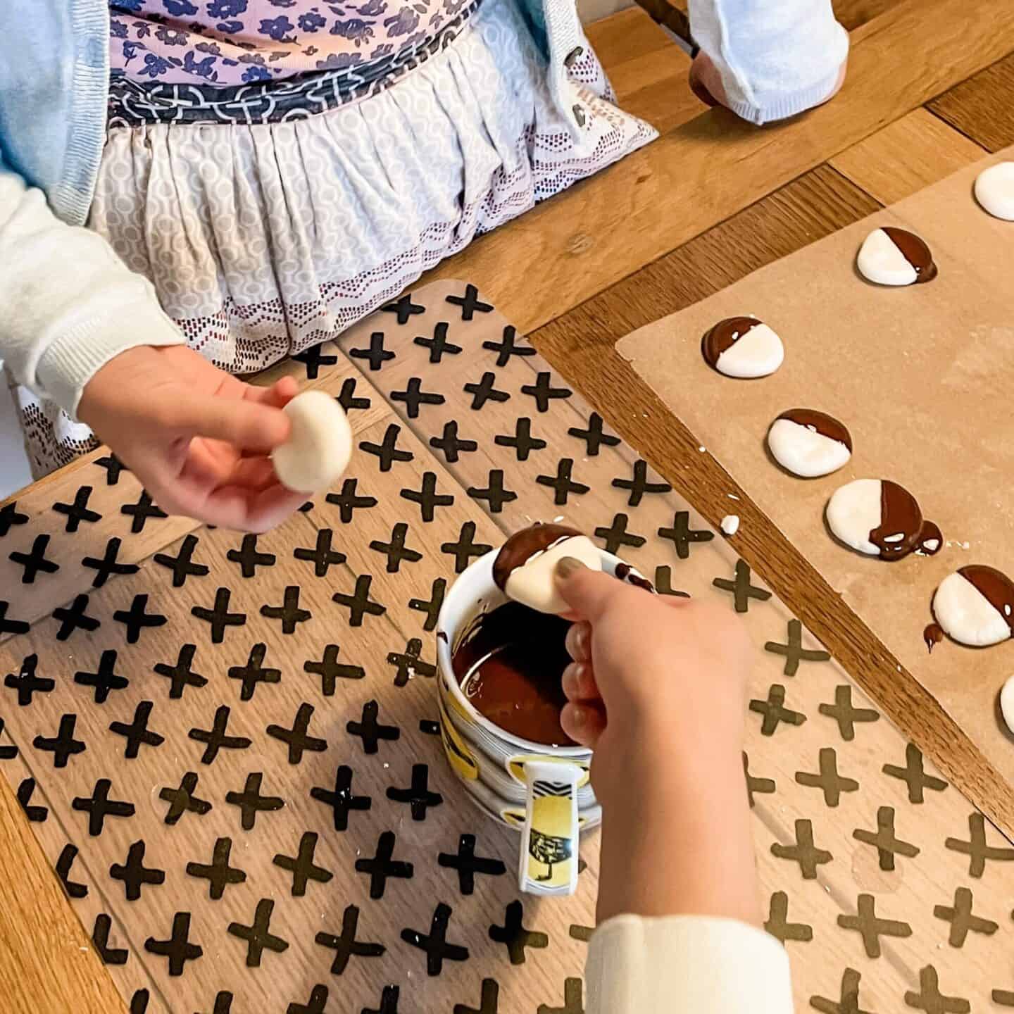 Children dipping peppermint creams into a mug of melted dark chocolate