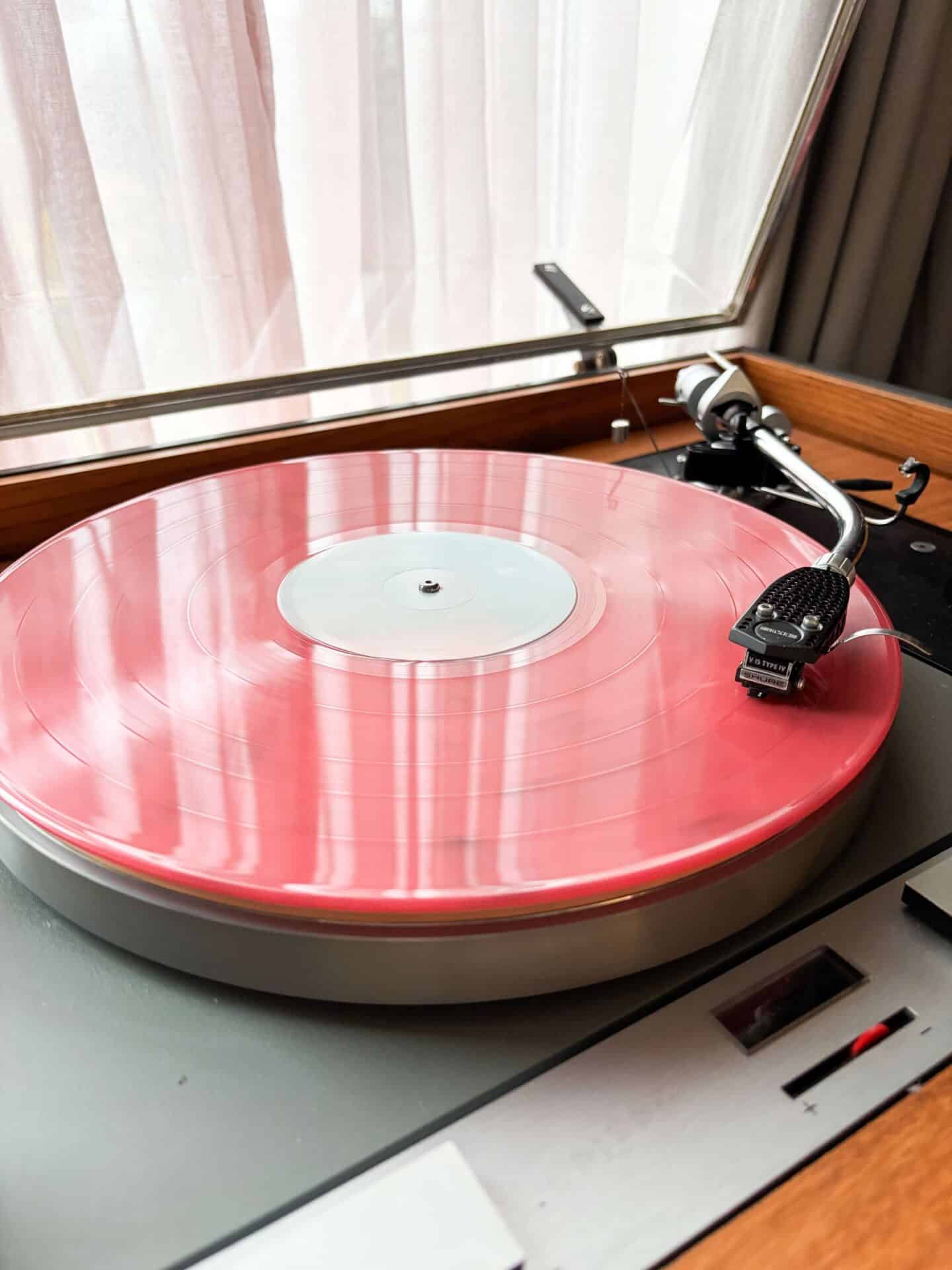 The best way to go analogue - listening to vinyl! A pink vinyl album being played on a wooden record player
